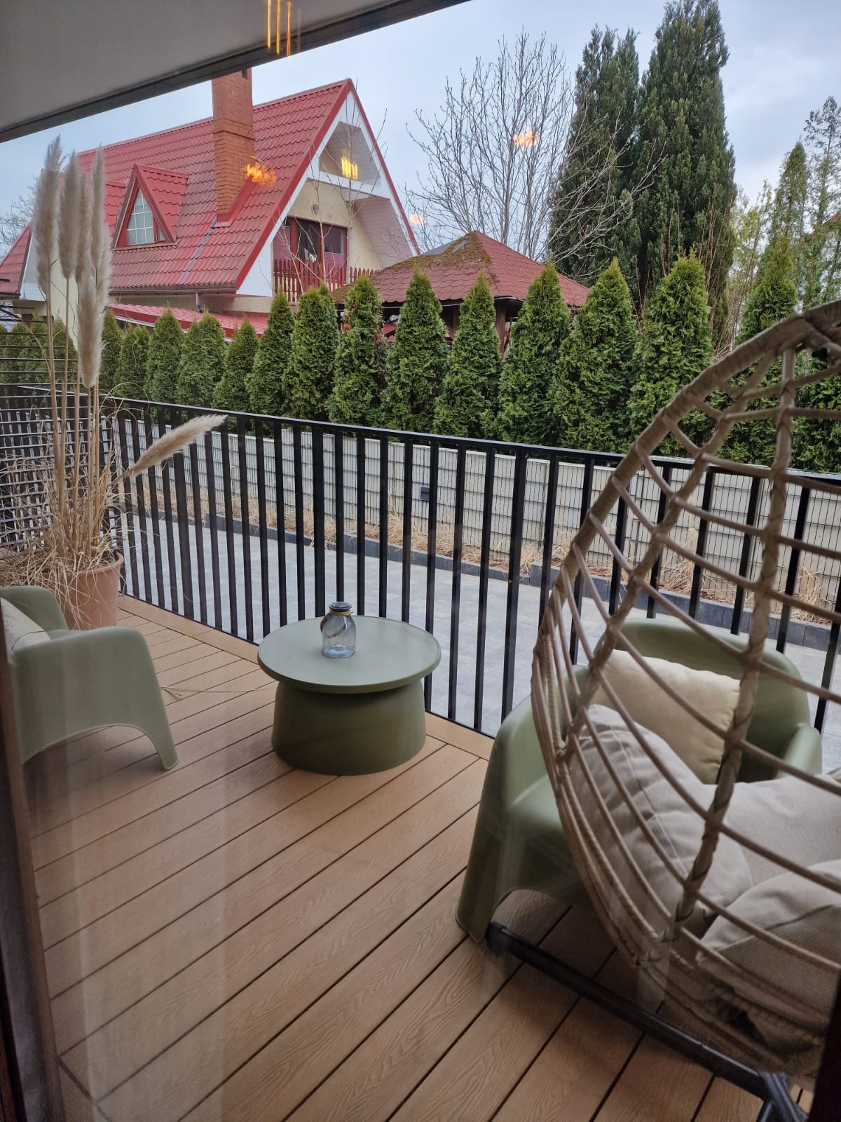Taras apartamentu z fotelem wiszącym i widokiem na zieleń